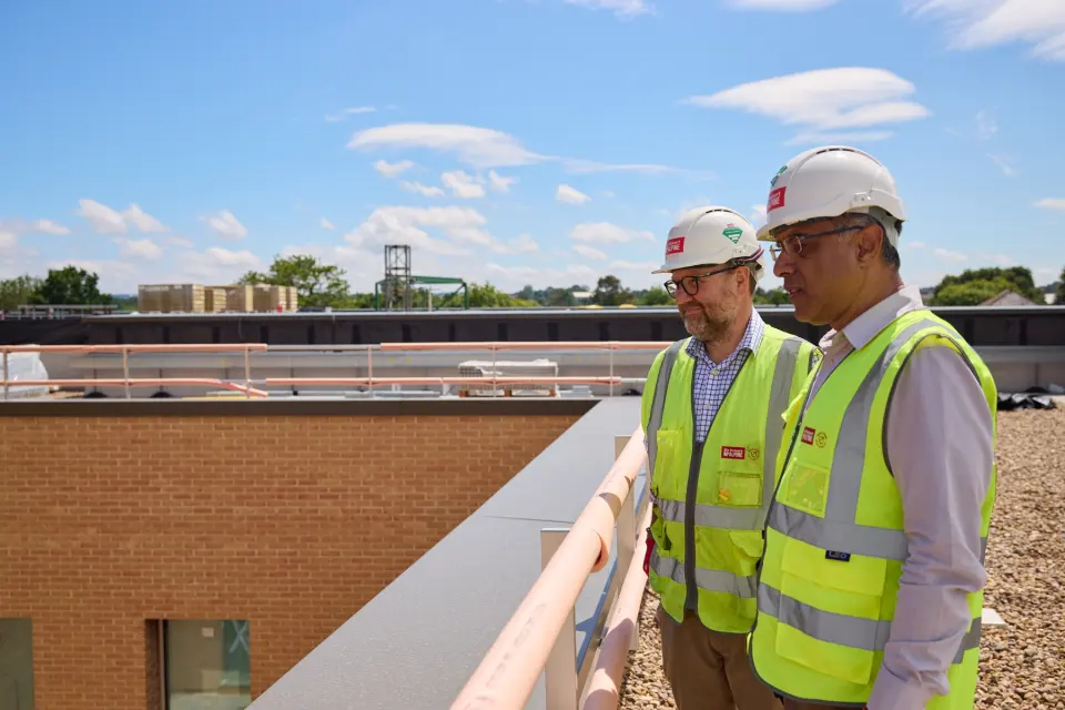 Two colleagues in hard hats on a roof terrace