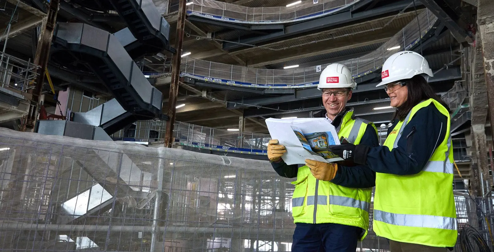 Two Sir Robert McAlpine engineers reviewing drawings inside a building under construction
